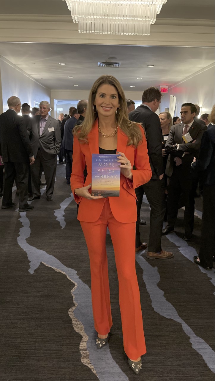Jen in orange suite holding a copy of More After The Break