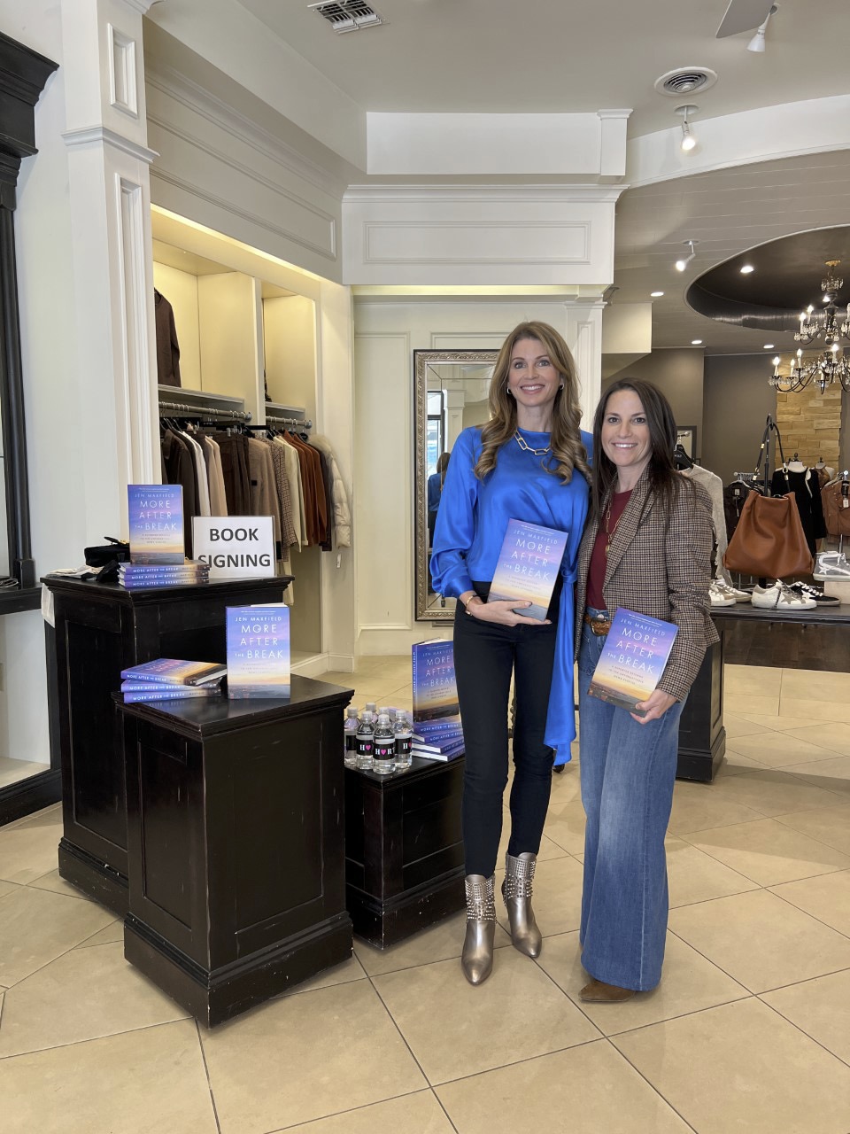 Jen in blue top and gold boots with a book signing attendee